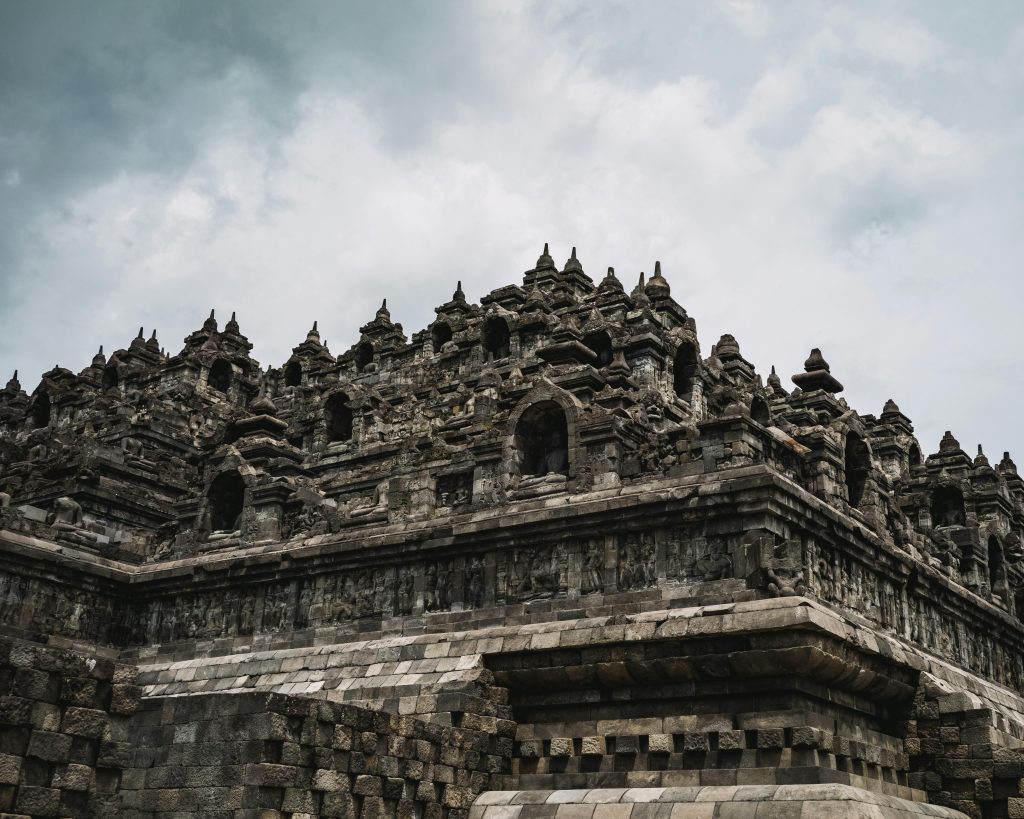 Majestic view of the ancient Borobudur Temple, showcasing intricate stone carvings under a cloudy sky.
