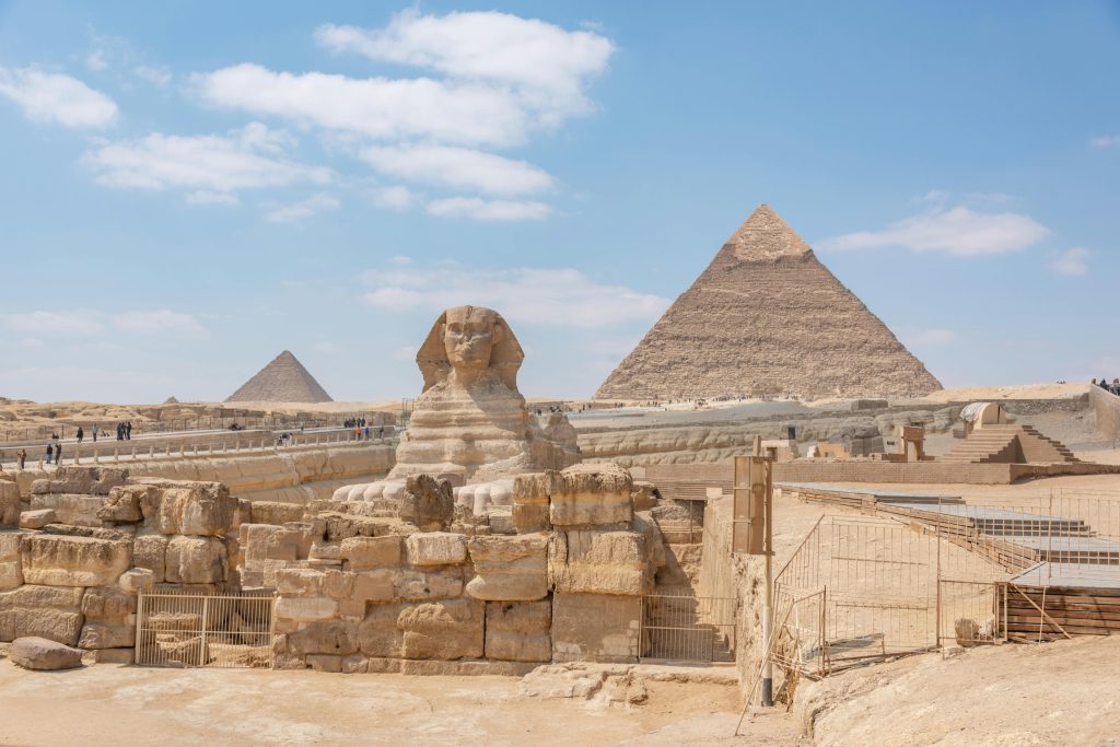 Iconic view of the Great Sphinx and Giza Pyramids in Egypt under a clear blue sky.