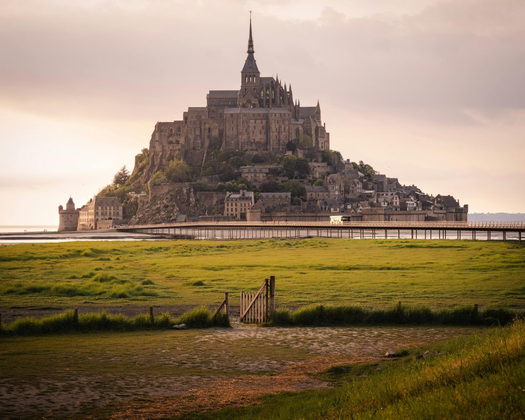 Experience the enchanting view of Mont Saint-Michel, a landmark in France, surrounded by tidal waters at sunset.